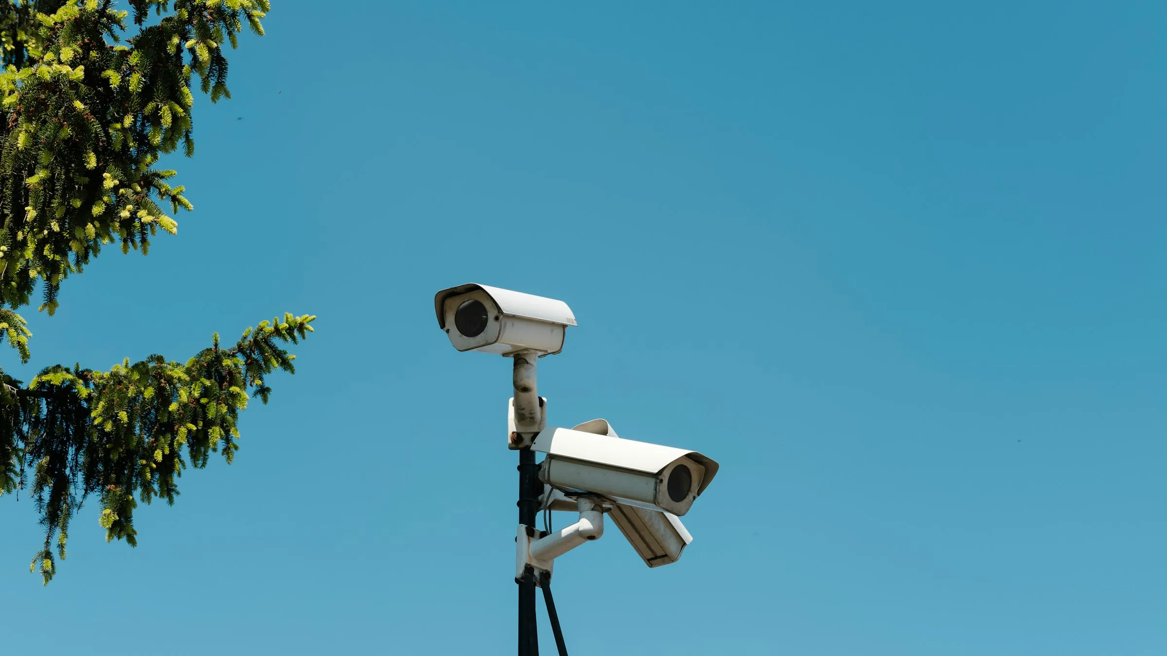 Security cameras mounted on a pole against open sky, watching over a site