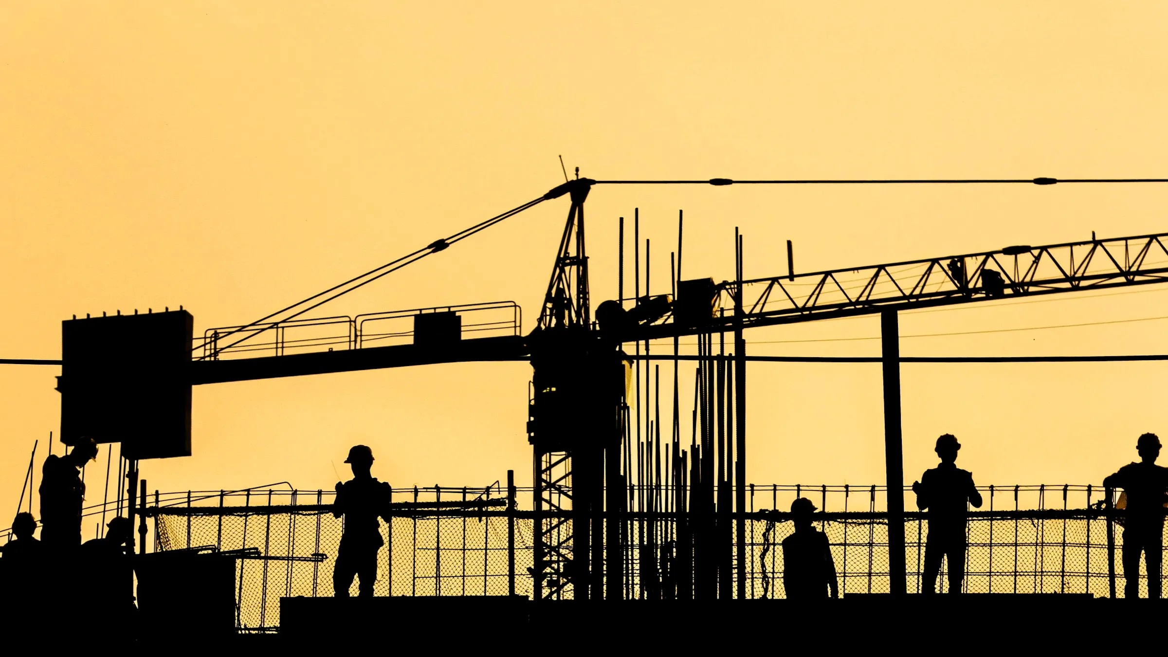 Work crew silhouetted on an unpowered job site at sunset