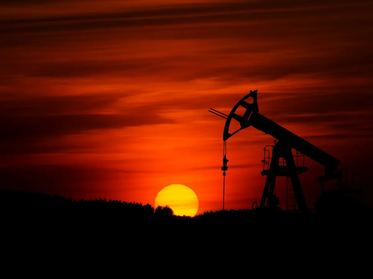 Oil pump jack silhouetted against a red sunset